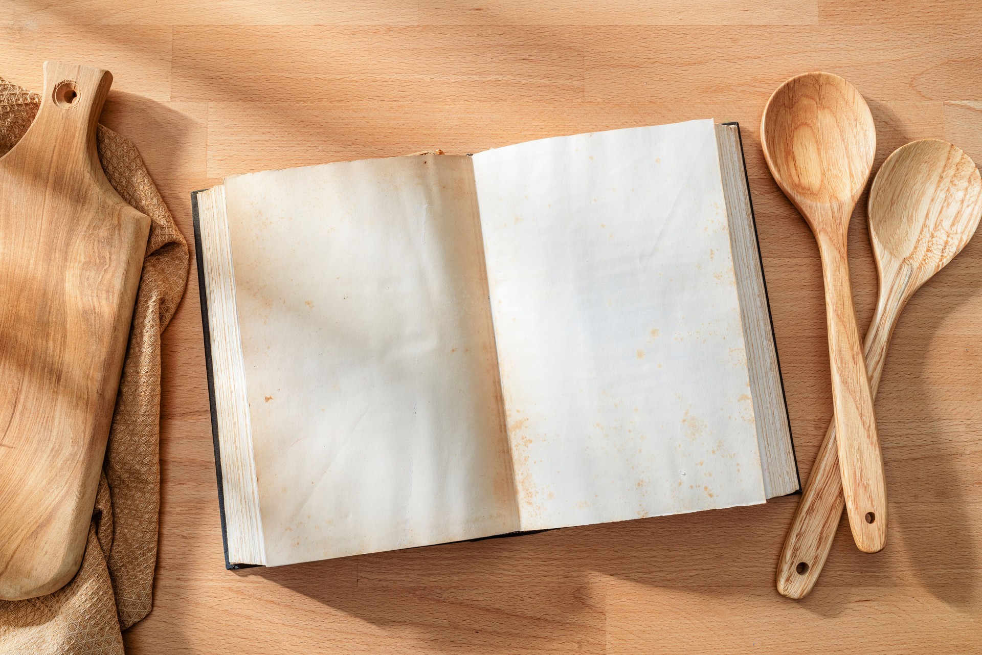 Open cookbook with blank pages shot from above on wooden table. Copy space on book